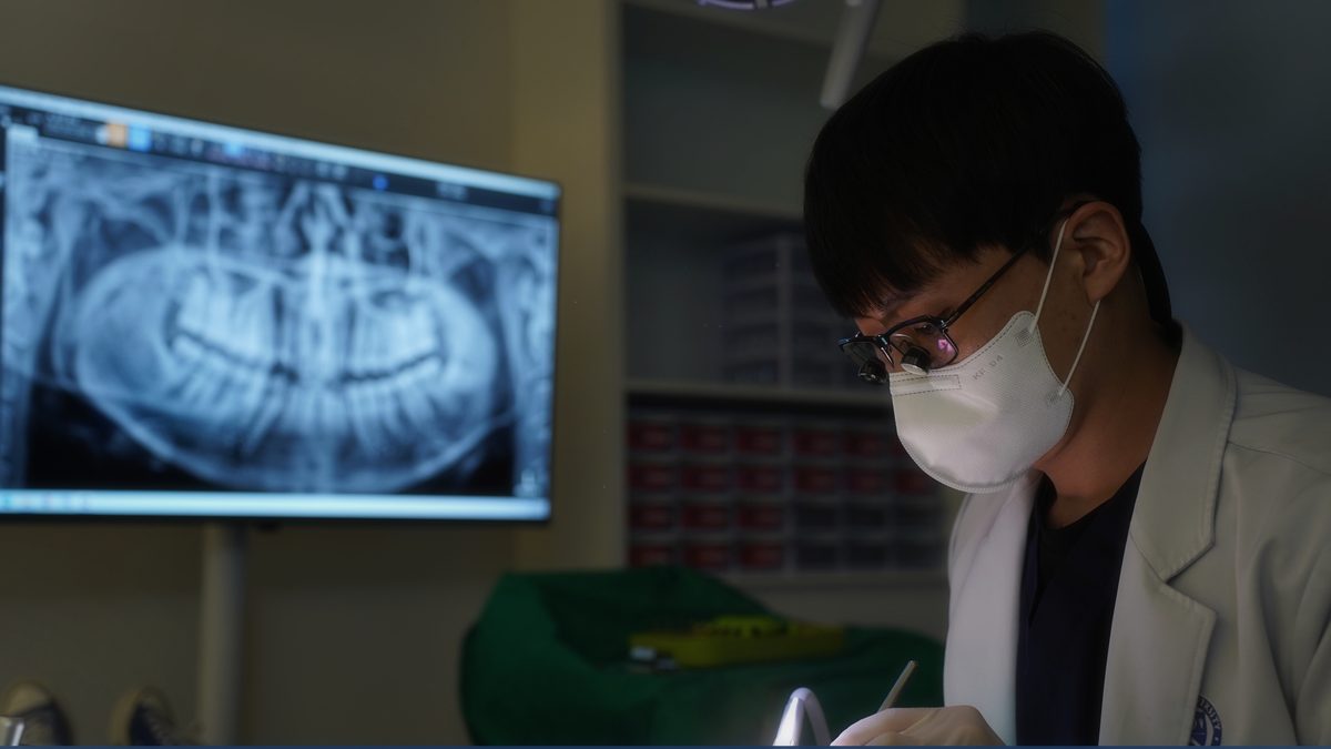 연세더튼튼치과의 야간 진료 장면 — 모니터의 파노라마 영상을 곁에 두고 진료에 집중하는 의료진